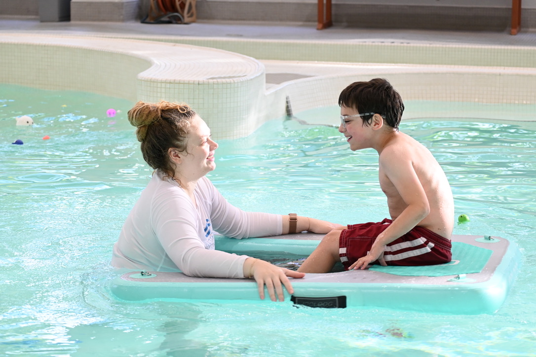 Dr. Kristen Kilroy assisting a child in the pool during an aquatic therapy session